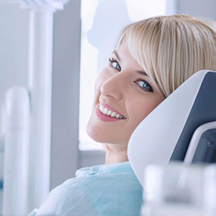 Happy patient in dental chair smiling at dentist appointment in modern office.